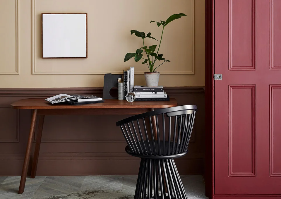 Holztisch mit Pflanze vor dem sich ein Stuhl befindet