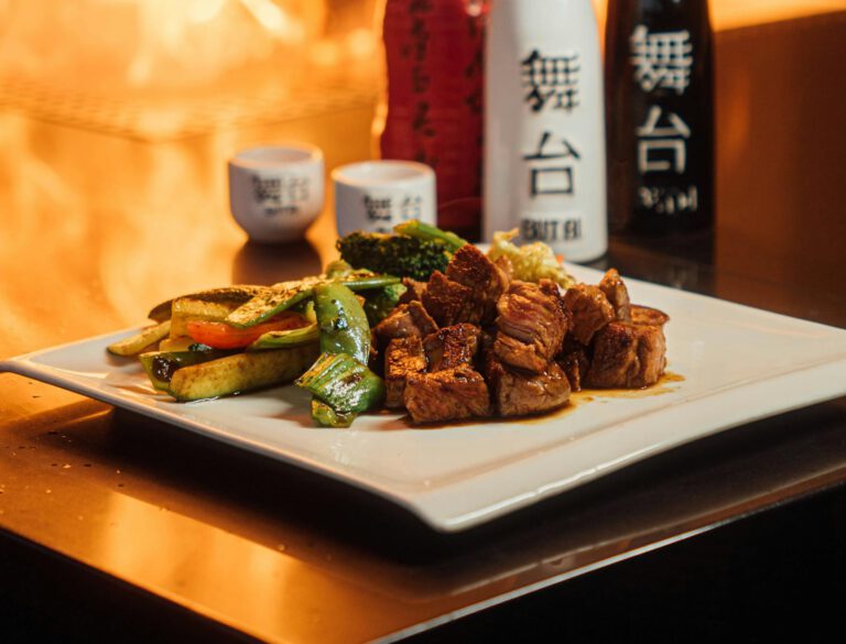 Sizzling teppanyaki beef with vibrant vegetables and fiery display.